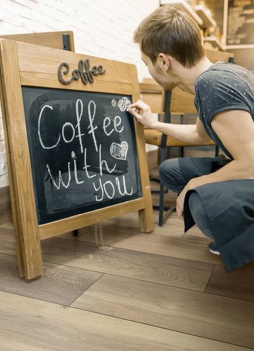 Coffee with you, writes in chalk on blackboard the young male owner of the coffee house